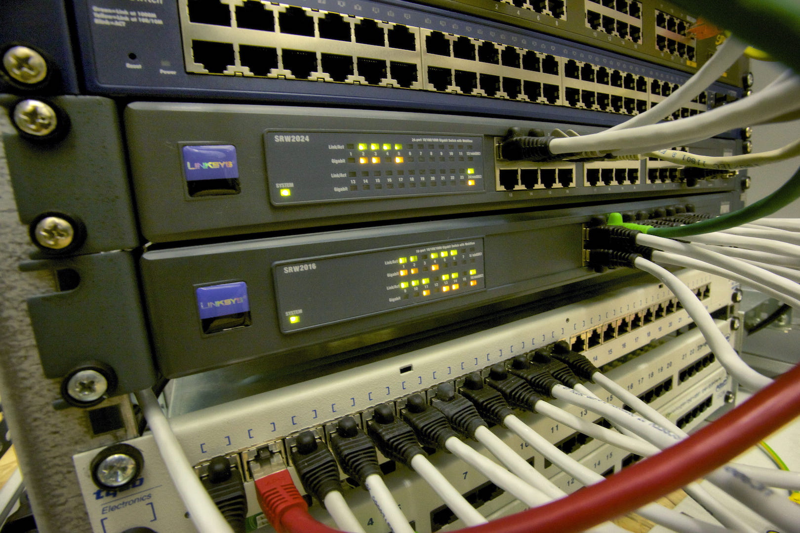 A stack of boxes installed in a rack, with blinking lights and dozens of network cables coming in and out.